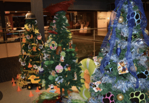 Three Christmas trees are decorated with ornaments and lights.